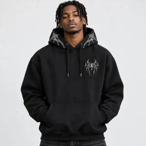 Black American male model wearing the black Chrome Crawler Hoodie with chrome spider chest graphic and hood web accents