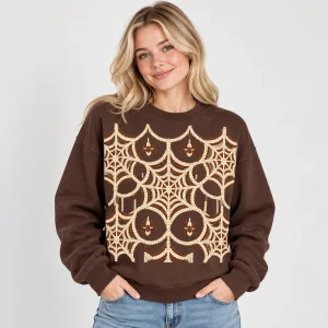 Blonde woman wearing the chocolate brown Knit Web Illusion spider web sweater with oversized cream knitted-look web graphic