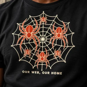 Close-up of cream and rust Our Web Family spider web print showing detail against black fabric