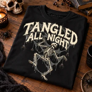 Folded black oversized skeleton spider shirt on wooden table with dancing skeleton and spider web print visible