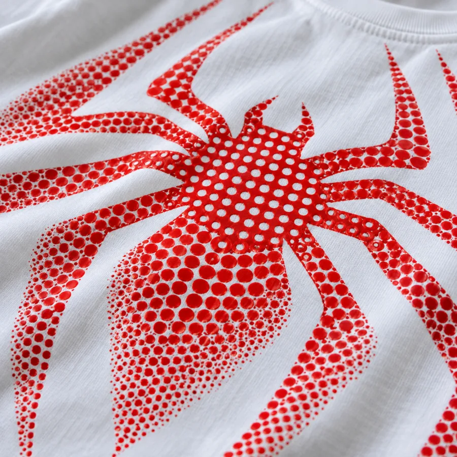 Close-up of red halftone dots fading in the spider emblem