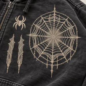 Close-up of cream archival spider web print on washed charcoal cotton hoodie fabric