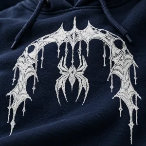 Close-up of white Web Hood System spider and web print on textured deep navy hoodie fabric